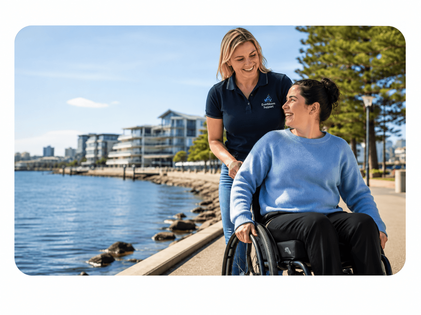 A support worker and participant walking together along a waterfront promenade