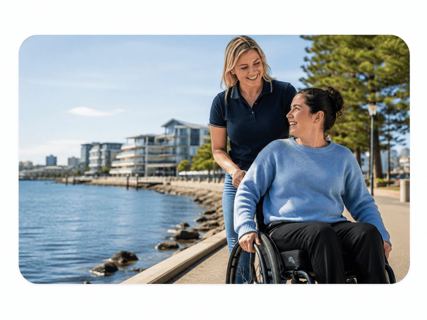 A support worker and participant walking together along a waterfront promenade
