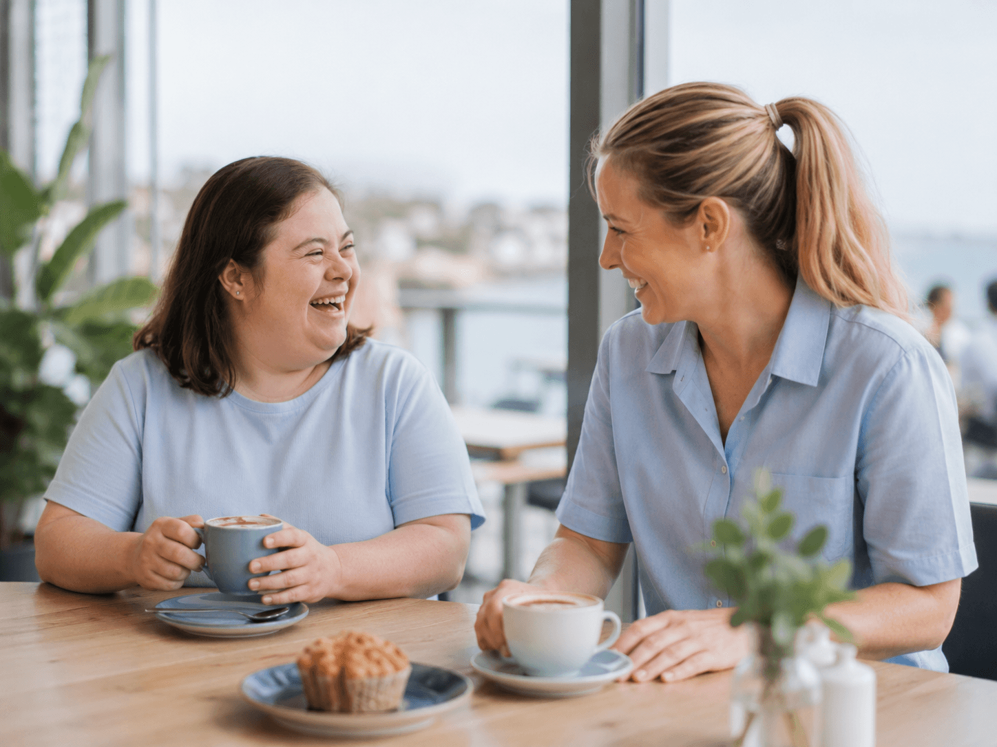 Two women sharing coffee and a laugh together at a café